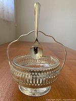 Front view of the glass bowl with silverplated pedestal stand and spoon hanging from the handle