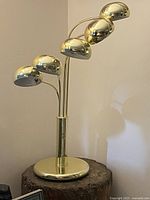 Full view of lamp showing round brass base, central stem splitting into five curved arms with orb shades