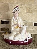 Full view of the figurine showing the princess seated with a doe on a maroon base.