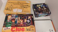 Photo showing three board games: The Simpsons Clue, Smash Up, and The Worst Case Scenario Survival Game (English edition).