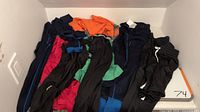 Photo showing a collection of tween sportswear including leggings in multiple colors, quick dry shirts, merino wool base layers (tops and bottoms) and black soccer shorts.