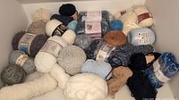 Photo depicting a large assortment of yarn balls in multiple colors and types, some with labels