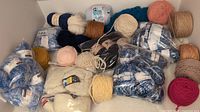 Photo showing various mixed yarn balls, some in original packaging and multiple colors visible.