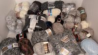 Photo showing multiple skeins and balls of yarn in assorted colors and textures stacked closely.