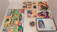 Photo of assortment of wooden puzzles, card game, and dry erase board arranged on flat surface