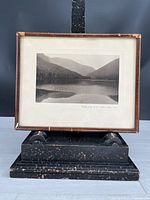 Front view of framed black and white photo showing a lake and mountain scenery.