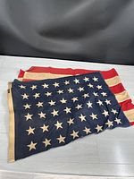 Folded American flag showing red and white stripes along with blue canton featuring white stars.