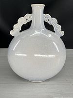 Front view of the white speckled ceramic moon flask, showing rounded body and neck with ornate handles attached.