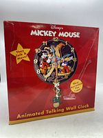 Front of the red Disney Mickey Mouse animated talking wall clock box showing image of clock with characters and text 'They Talk & Move!' and 'They Announce The Time!'.