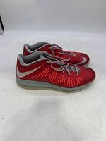 Pair of red Nike LeBron 10 Low basketball sneakers viewed from the side on white background