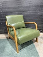 Front right angled view of the green vinyl lounge chair, showing wood frame and cushion condition