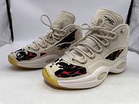 Left and right sneakers with visible black and red camo skull pattern, off-white upper, and cream soles.
