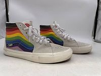 Side view of both Vans high top sneakers showing rainbow stripe design and white rubber sole.