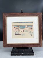 Full view of the framed art print on a black stand, showing the entire rustic wood frame and white matting with the artwork centered.