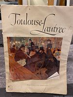 Front cover of Toulouse-Lautrec art book showing a famous scene with seated figures and title on top.
