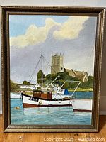 Full view of the oil painting showing a boat on the water with a church and cloudy sky background, framed in a gold-tone frame.
