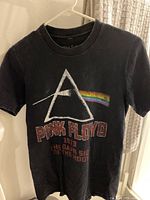 Front view of the Black Pink Floyd t-shirt hanging on a hanger showing the full design.