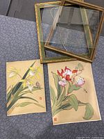 Two vintage Chinese floral paintings, unframed, alongside two old frames.