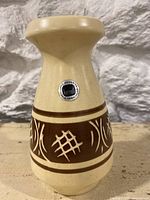 Full view of beige pottery vase with narrow neck and brown patterned band.