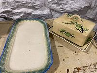 Full view of both the Japanese vintage butter dish with lid and the matching rectangular tray on a beige surface with a stone wall background