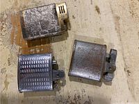 Top-down view of three vintage metal lighters showing textures, wear and size