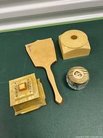 Photo showing closed hair catcher, ivory container with lid, Yardley glass jar, and celluloid hand mirror backside