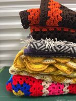 Stacked view of four vintage blankets showing colors and textures including crochet and woven designs