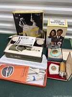 Six vintage hygiene and bathroom items showing original boxes and various components including cords, attachments, and manuals.