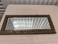 Full view of the rectangular mirror showing embossed brass frame and beveled edges.