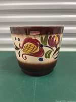 Front view of vintage Scheurich flowerpot showing the Scheurich sticker and floral hand-painted design, brown glazed rim and base.