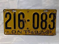 Front view of 1924 Ontario license plate showing number 216-083, rust spots and paint wear.