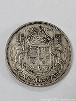 Front side of the 1944 Canadian 50 cents silver coin showing the detailed crowned shield, lion and unicorn holding flags, and maple leaf symbols at the bottom.