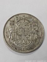 Obverse of the 1951 Canadian silver half dollar showing the Coat of Arms with two supporters, a lion and a unicorn, flags, crown, and leaf motifs.