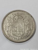 Close-up of one 1957 Canadian 50 cents coin showing coat of arms and denomination.