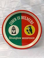Top view of vintage Strongbow and Bulmers Woodpecker cider metal tray showing colorful graphics and some surface wear.