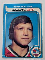 Front side of the 1979-80 Bobby Hull OPC hockey card showing his portrait in Winnipeg Jets uniform with blue background and team logo.