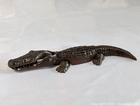 Full view of the antique cast iron alligator nutcracker on fabric background showing entire body and tail.