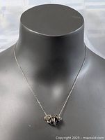 Full view of the necklace showing chain and clustered heart pendants on a black bust.
