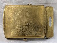 Front view of brass Canada Military Canadian Airborne belt buckle showing parachute, maple leaf and wings embossed in the metal with banner.