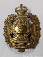 Front view of the brass military badge showing the detailed stag head emblem and surrounding maple leaves with crown top