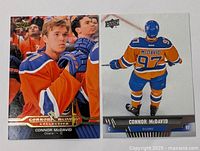 Pair of Connor McDavid Edmonton Oilers hockey cards shown on table, one front view and one rear view.