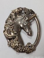 Front view of the vintage Gorham sterling silver unicorn pendant featuring detailed floral decorations and the unicorn head in profile.
