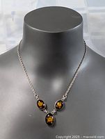 Classic MCM sterling silver necklace displayed on bust model, showing chain and three rose resin pendants.