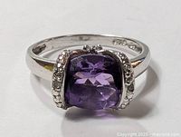 Front view of sterling silver ring with cushion-cut purple amethyst and detailed silver accents on either side of the stone.
