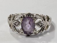 Front view of the sterling silver ring with oval purple amethyst gemstone and detailed openwork sides.