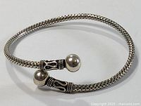 Full view of sterling silver bracelet showing woven band and ball end caps with decorative oxidized silver accents.