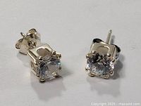 Close-up front angle of one crystal stud earring showing round clear stone and silver prong setting