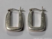 Front view of the pair of rectangular sterling silver earrings showing their shape, finish, and latch back closure.
