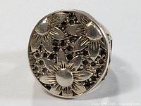 Front angle of the sterling silver ring with three sunflowers and textured background.