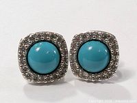 Close-up photo showing vintage sterling silver earrings with turquoise encrusted center and beaded border.